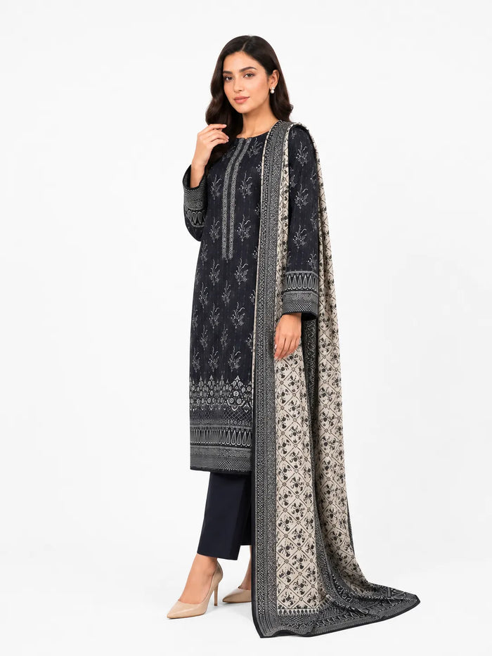 A woman modeling a traditional South Asian outfit consisting of a black kurta with intricate silver embroidery, matching black trousers, and a long draped dupatta with a beige and black floral pattern, set against a plain white studio background.