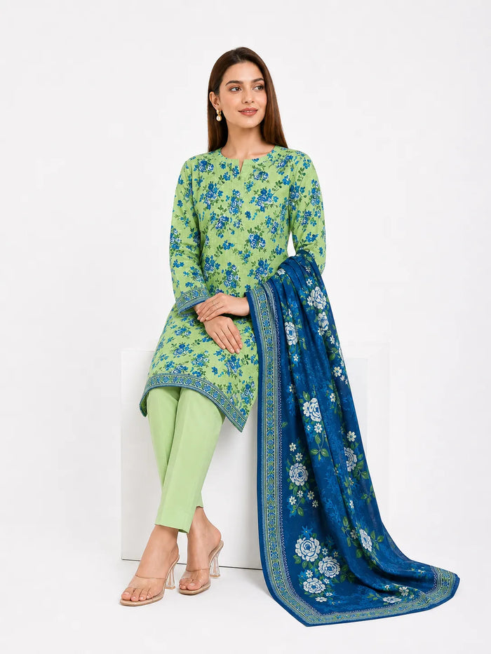 A woman models a three-piece Indian ethnic wear set consisting of a lime green kurta with blue floral print, matching light green pants, and a royal blue dupatta with white floral motifs and gold borders, set against a plain white background.