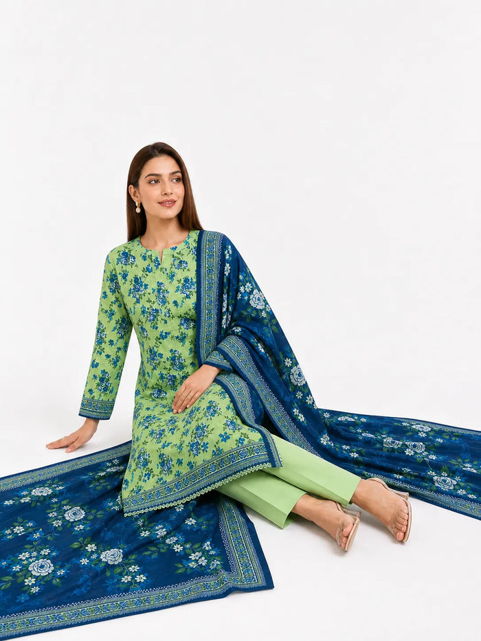 A woman models a traditional Indian salwar kameez suit set featuring a light green kurta with blue floral embroidery, light green trousers, and a dark blue dupatta with intricate gold and white border patterns, set against a plain white studio background.