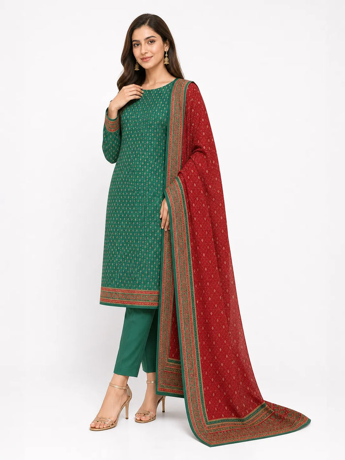 A woman modeling a traditional Indian salwar kameez set in green with a red dupatta featuring gold patterns and borders, set against a plain white studio background.