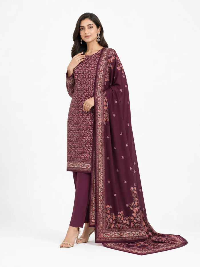 A woman models a traditional three-piece salwar kameez suit in deep maroon with intricate gold and silver embroidery. The set includes a long-sleeved tunic, matching trousers, and a draped dupatta with floral patterns and borders, photographed against a clean white studio background.